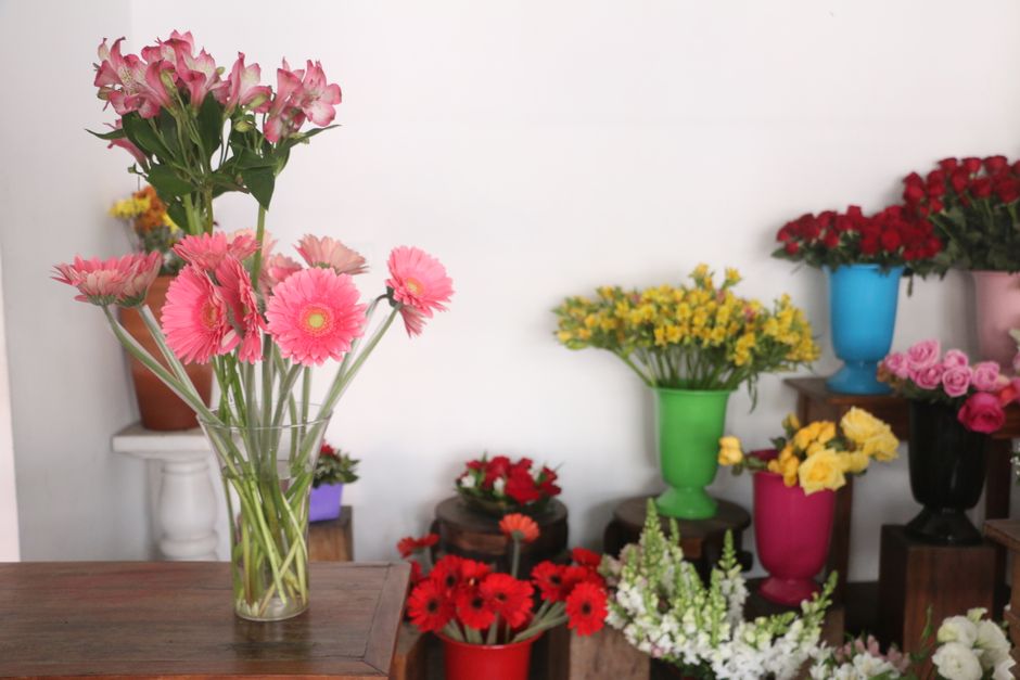 Kleurrijke bloemenarrangementen op een boekenplank.